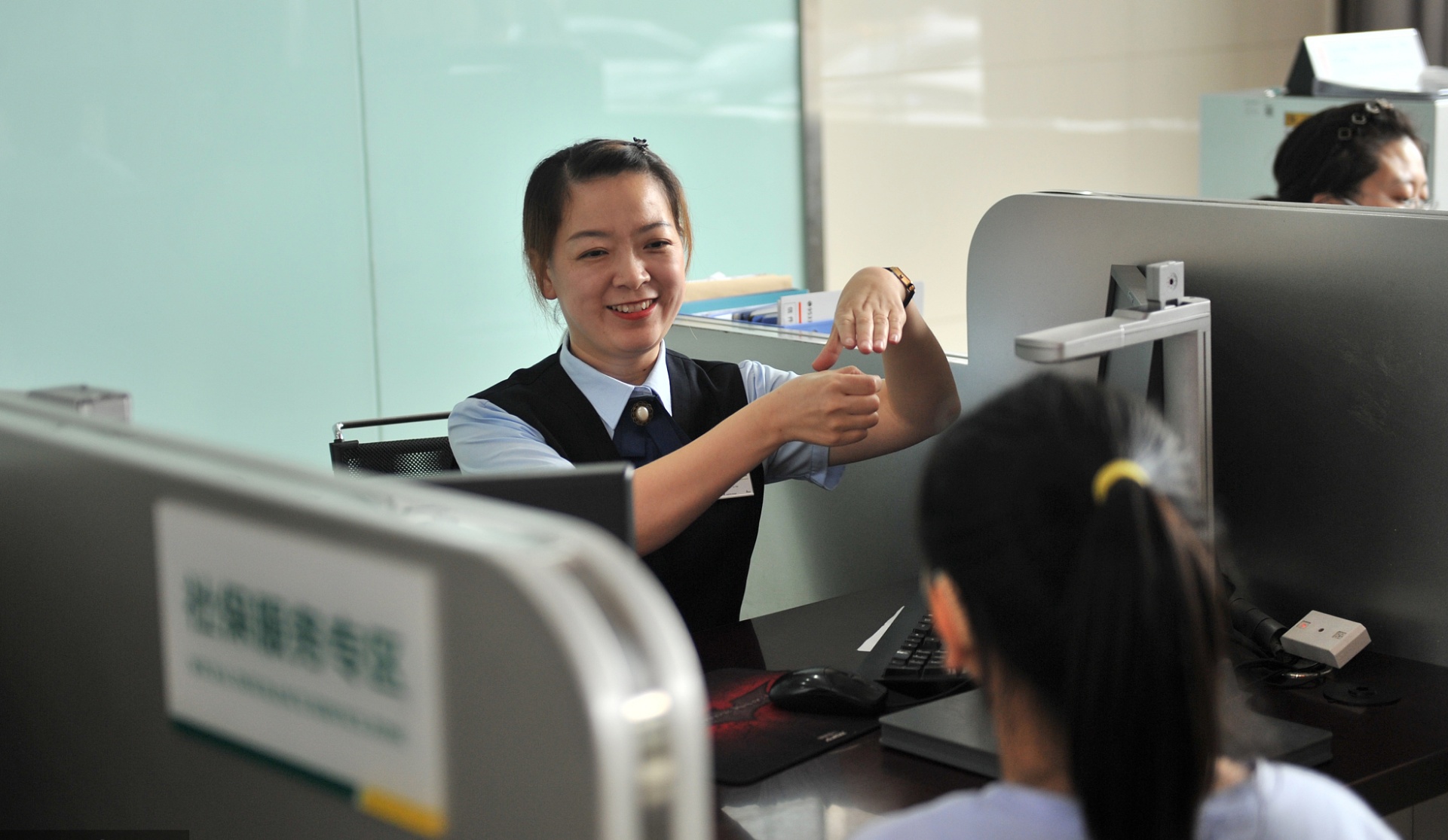 2021年7月21日,山西省太原市,邮储银行工作人员为聋哑客户提供手语