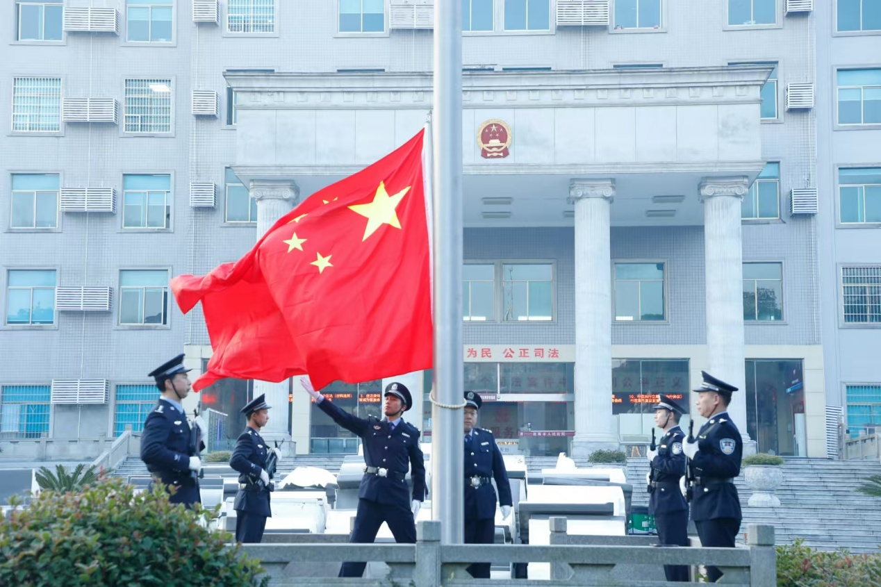 在激昂的国歌声中,擎旗手挥臂扬旗,干警们面向国旗庄严敬礼,注视着